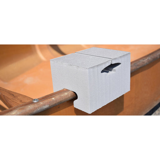 A white foam block with a slot cutout, mounted onto a wooden gunwale inside a canoe