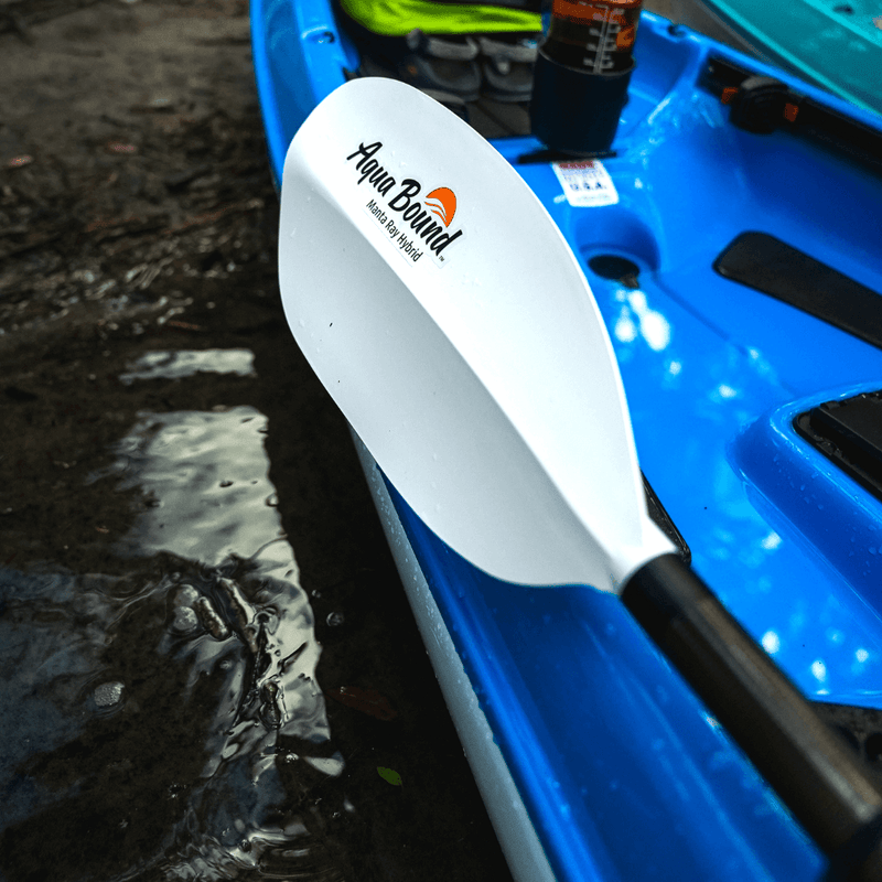 Paddle with Aqua Bound logo on a blue kayak by a body of water