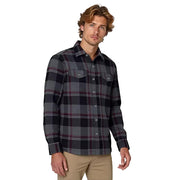 Man wearing a plaid shirt and beige pants on a gray background