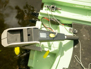 A portable battery sitting in a green boat with water in the background.