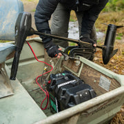 A person working on a boat with a battery box in the bottom of it.
