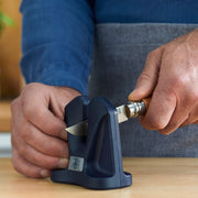 Person using a black manual knife sharpener to sharpen a small pocket knife.