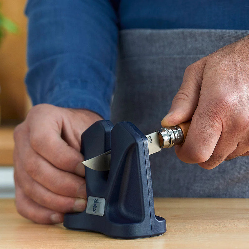 Person using a black manual knife sharpener to sharpen a small pocket knife.