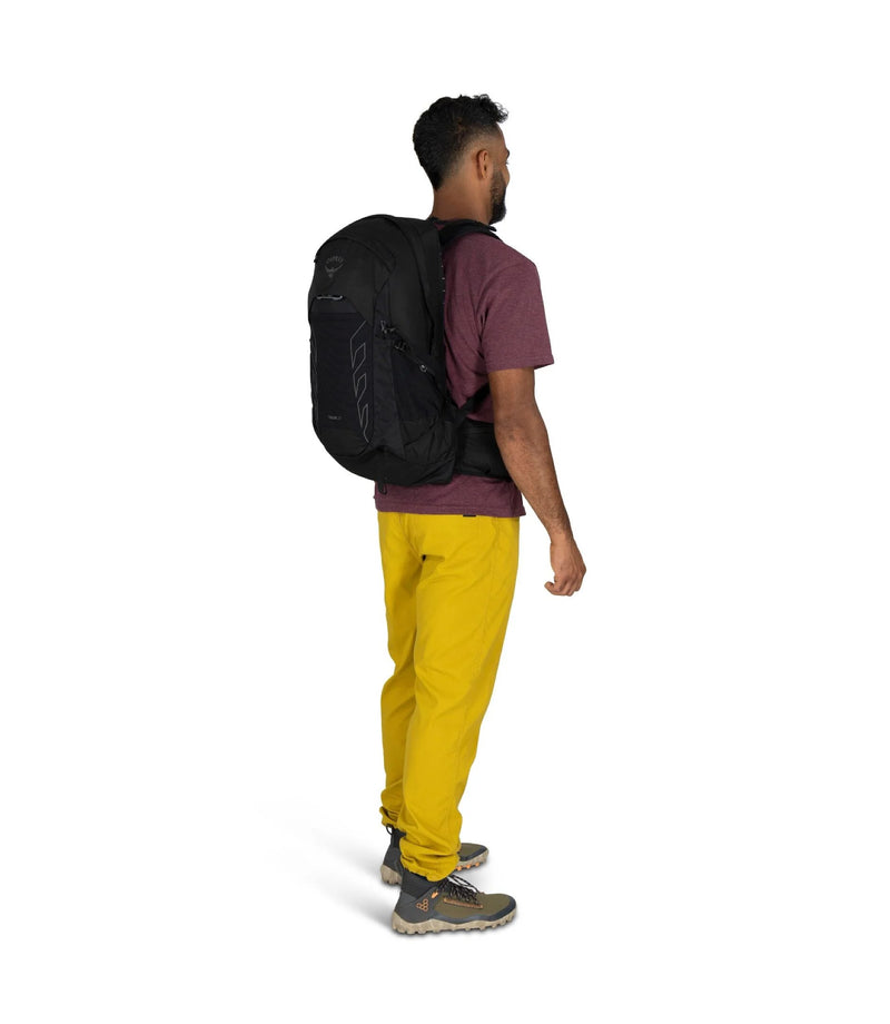 Person wearing a black backpack and yellow pants on a white background