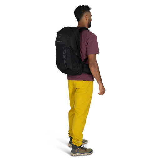 Person wearing a black backpack and yellow pants on a white background