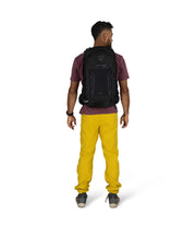 Man wearing a black backpack and yellow pants on a white background