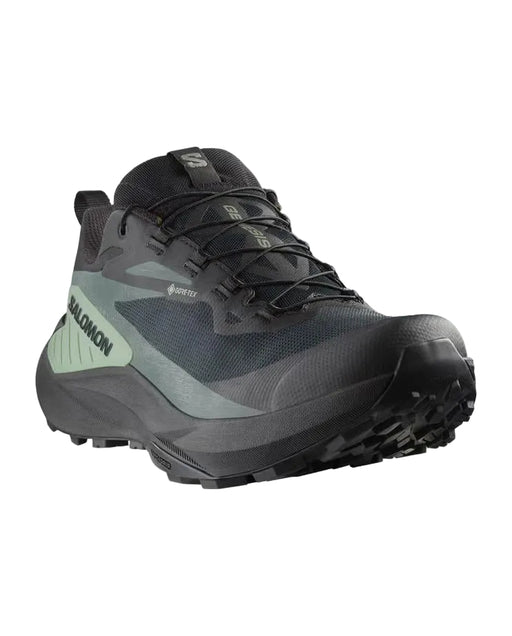 Black hiking shoe with green accents on a white background