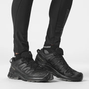 Black hiking boots worn with black pants on a white background