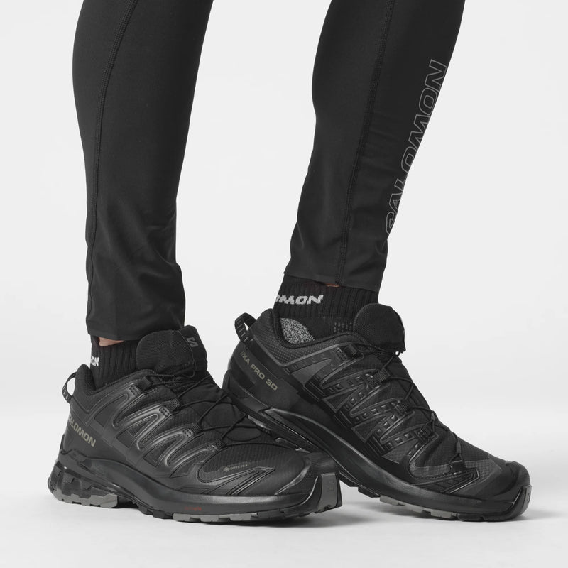 Black hiking boots worn with black pants on a white background