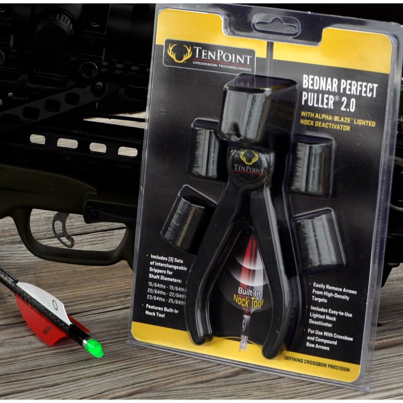 TenPoint Bednar Perfect Puller 2.0 in its original blister packaging, displayed on a wooden surface with a bow and arrow in the blurred background.