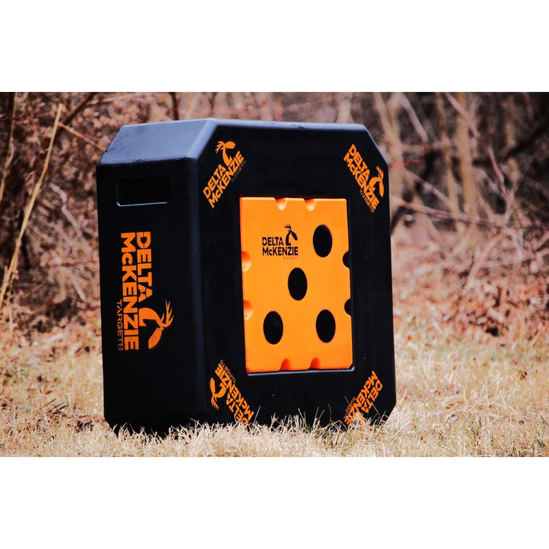 A black and orange Delta McKenzie target block standing outdoors on dry grass with trees in the background.