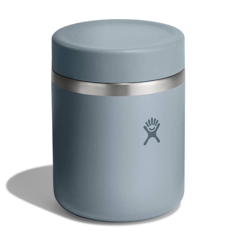A dusty blue insulated can cooler with a stainless steel band and the Hydro Flask logo, shown on a white background with a soft shadow.