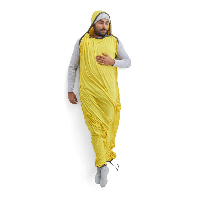Person wearing a yellow sleeping bag liner with a hood on a white background