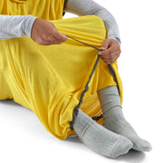 Person wearing a yellow garment with gray socks on a white background