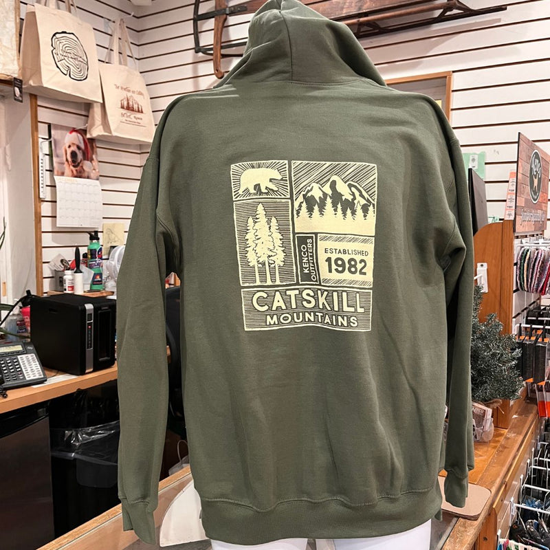 Green hoodie with 'Catskill Mountains' design on the back, displayed in a store setting.