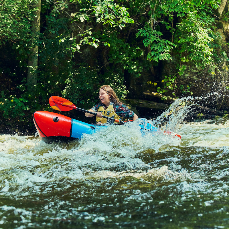 Person kayaking in a river with lush greenery in the background
