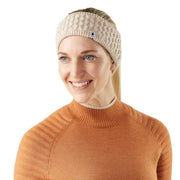 Woman wearing a beige knitted headband with a brand logo on a white background