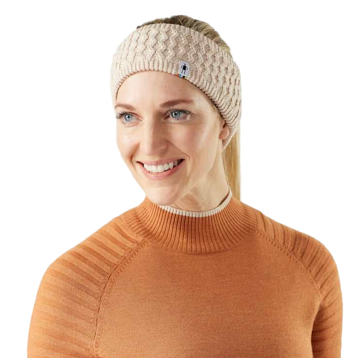 Woman wearing a beige knitted headband with a brand logo on a white background