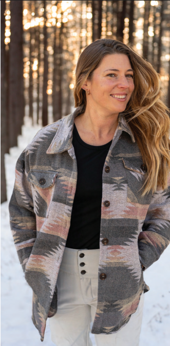 Woman wearing a patterned jacket in a snowy forest