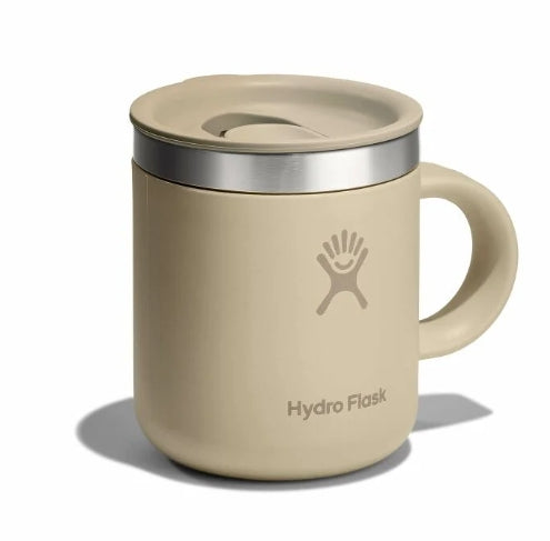Side view of a small tan travel mug with a Hydroflask logo on it on a white background.