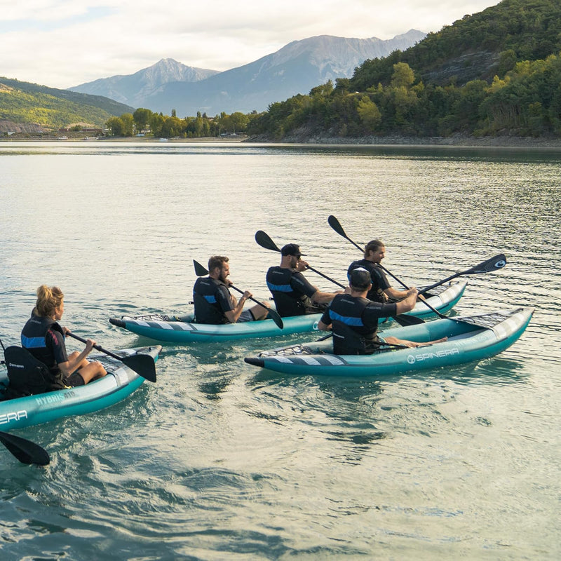 Group of people paddling in blue inflatable kayaks with white accents in a lake. 