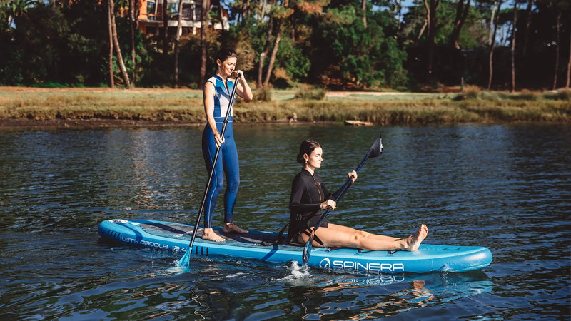 Two people paddleboarding on a lake with a visible brand logo.