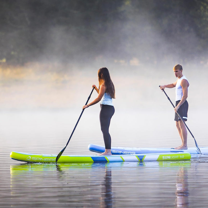 Man and woman standing on their yellow and blue paddleboards in a lake. 
