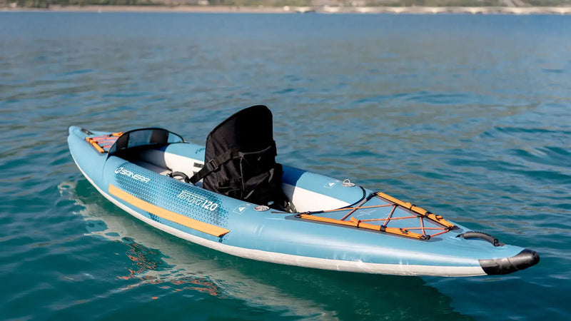 Blue inflatable kayak with orange and white accents sitting in a lake.