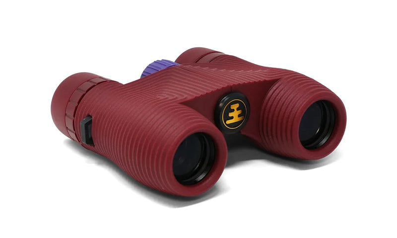 A red pair of binoculars with a purple dial on a white background
