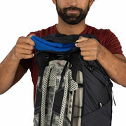 Person holding a black backpack with a blue item on a white background
