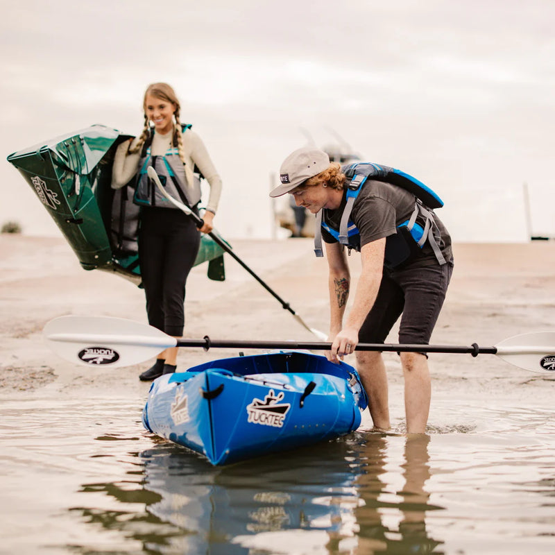 Two people with kayaks on a beach