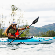 Woman paddling her blue and white kayak in a lake.