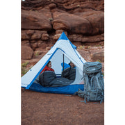 Man and woman sitting in a white and blue tent in a canyon.