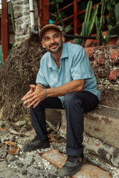 Man sitting on a stone ledge with a rustic background