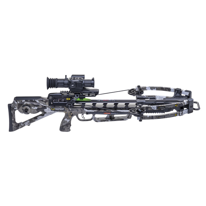 A crossbow with a black and gray camouflage stock, limbs, and grip, featuring a mounted scope and a green arrow nocked in the cable, shown against a plain white background.