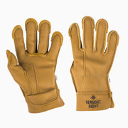 A pair of tan leather work gloves shown against a plain white background, displaying both the back of one glove and the palm/strap of the other. The right glove features the brand name 'VERMONT GLOVE' printed in black on the wrist cuff.