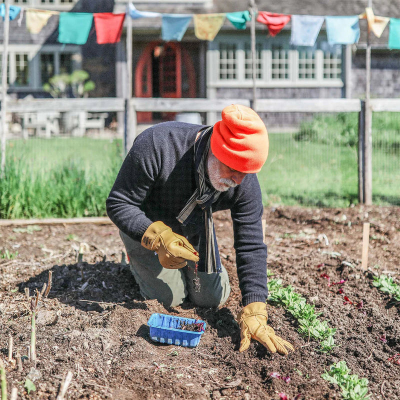 Person gardening in a plot with colorful flags in the background