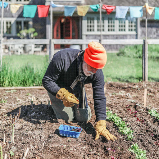 Person gardening in a plot with colorful flags in the background