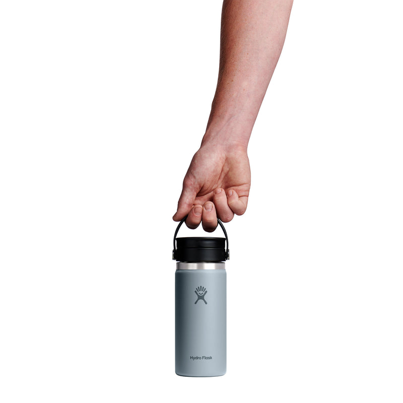 A hand holding the black handle of a light gray Hydro Flask water bottle against a solid white background.