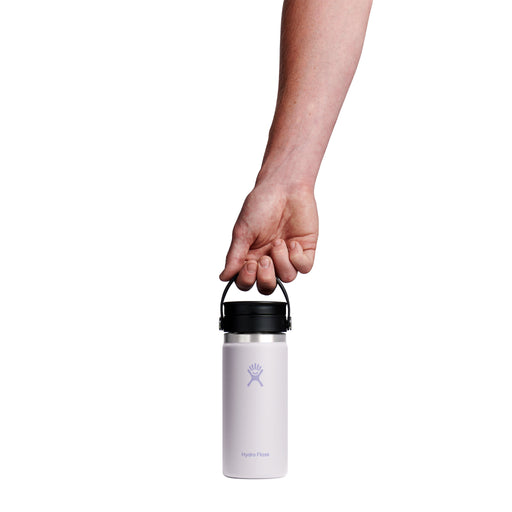 A hand holding the black handle of a Hydro Flask insulated water bottle against a solid white background.