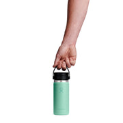 Hand holding a mint green water bottle with black lid on a white background