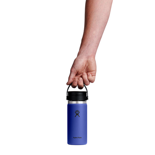 Hand holding a blue Hydro Flask water bottle with a black lid on a white background