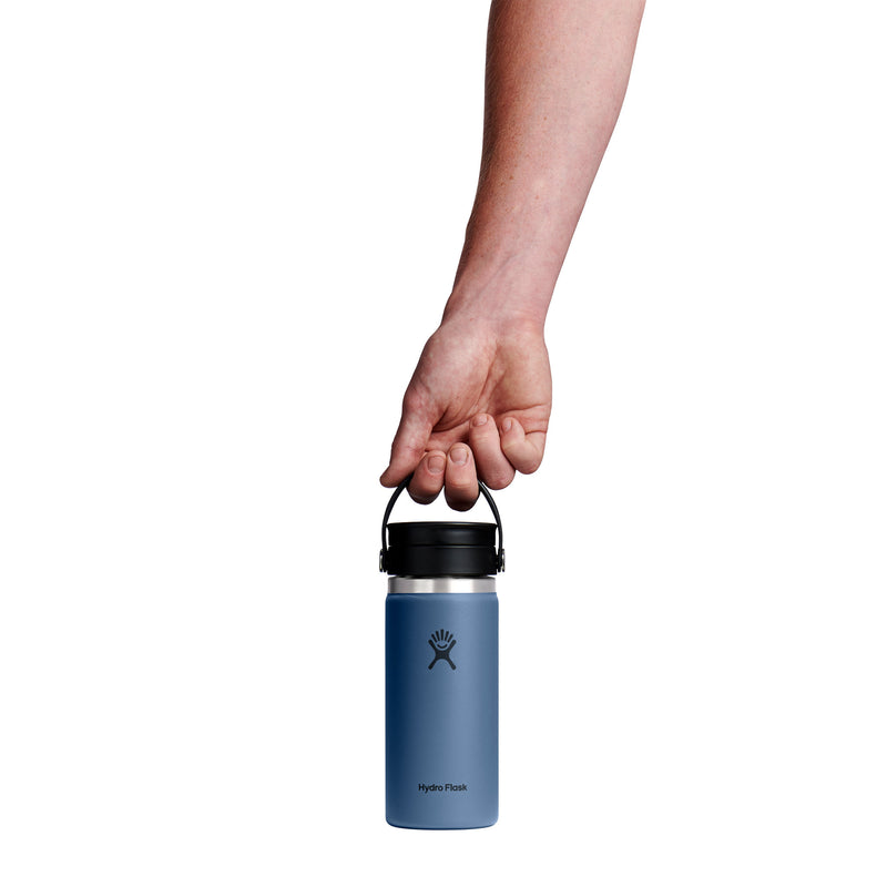 A hand holding the black handle of a blue Hydro Flask insulated water bottle against a solid white background.