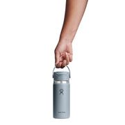 A hand holding the handle of a Hydro Flask insulated water bottle against a solid white background.