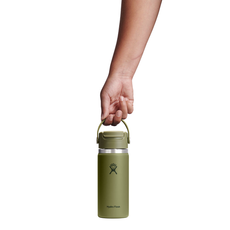 A hand holding the handle of an olive green Hydro Flask insulated water bottle against a solid white background.