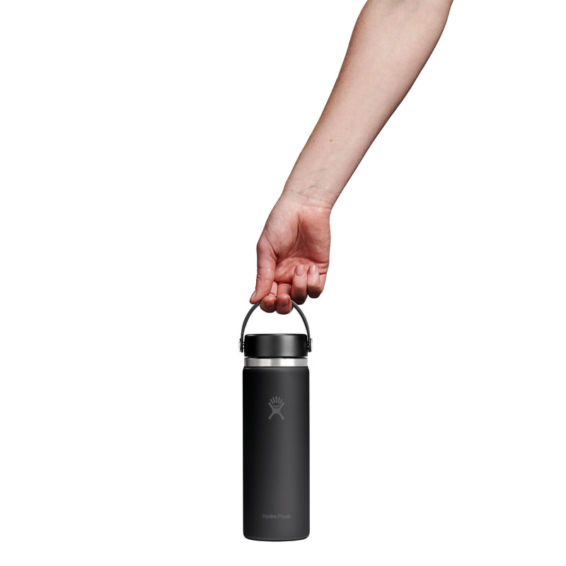 A hand holding the handle of a matte black insulated water bottle against a solid white background.