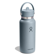 A Hydro Flask water bottle in a muted slate blue-gray color, featuring a matching blue-gray lid with a carry loop and a silver metal band near the top. The Hydro Flask logo is printed on the front, and the brand name is visible near the bottom, set against a clean white background with a soft shadow.