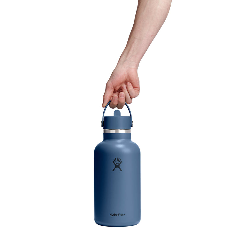 A hand holding the handle of a matte slate blue Hydro Flask water bottle against a solid white background.