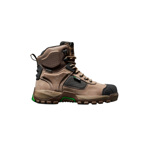 A single high-top work boot in tan and black with a small green accent near the sole, shown in side profile against a dark studio background with a blue glow beneath it.