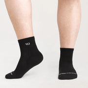 Black socks with a logo worn by a person on a light gray background